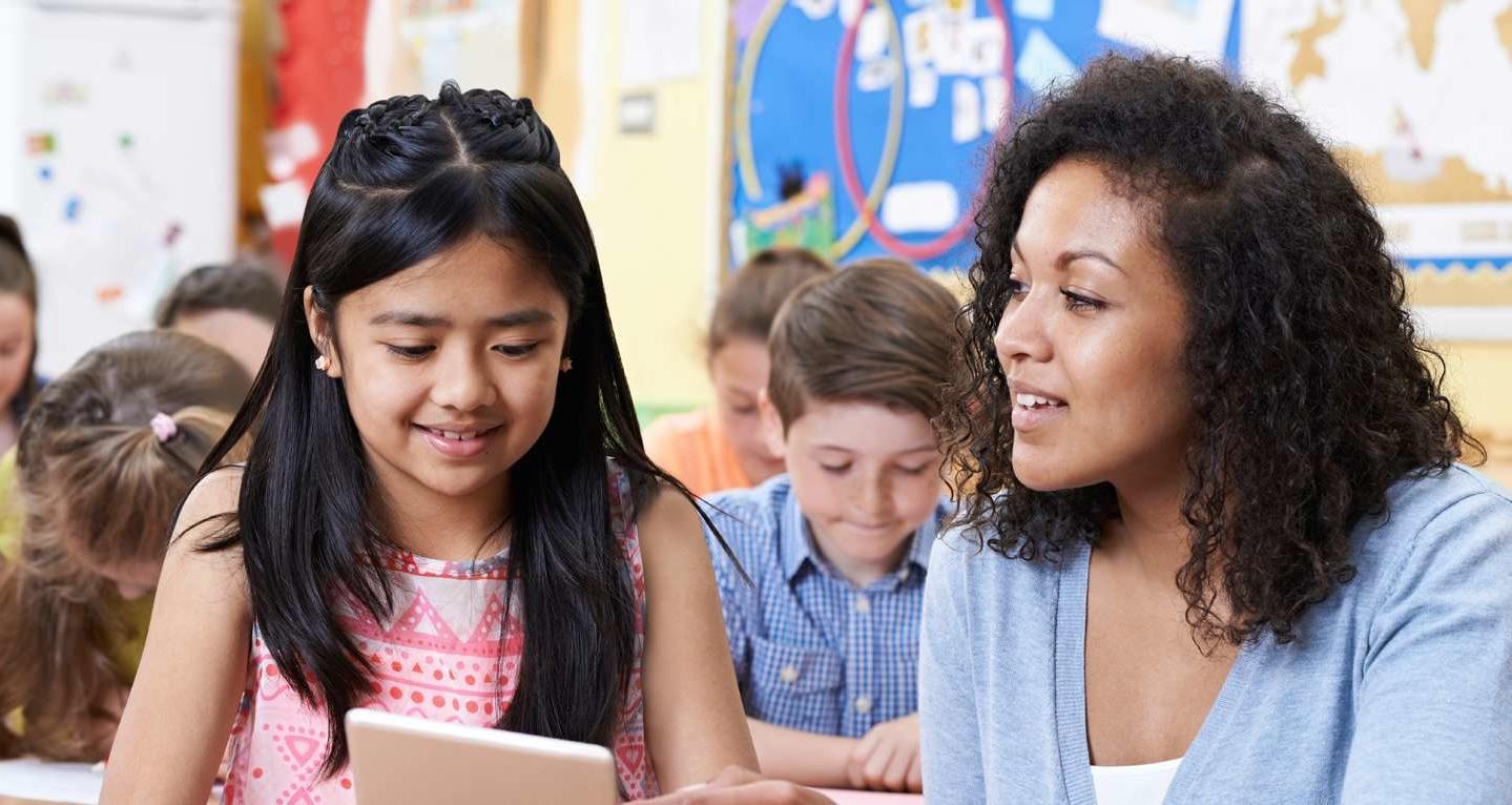 A teacher is working one-on-one with a young girl.